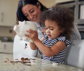 A mother watches as a child empties her piggy bank