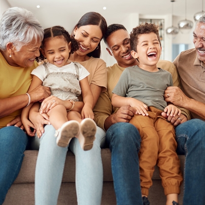 multi-generational family together on a sofa laughing and smiling